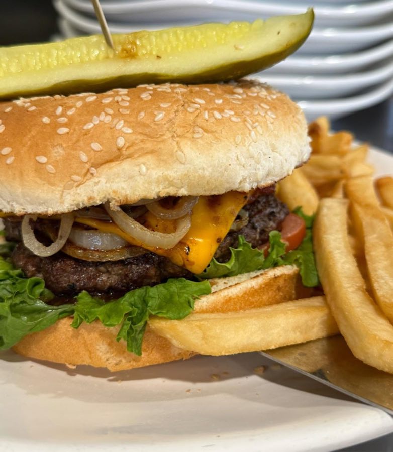 Cheeseburger with grilled onions, pickle spear, and fries