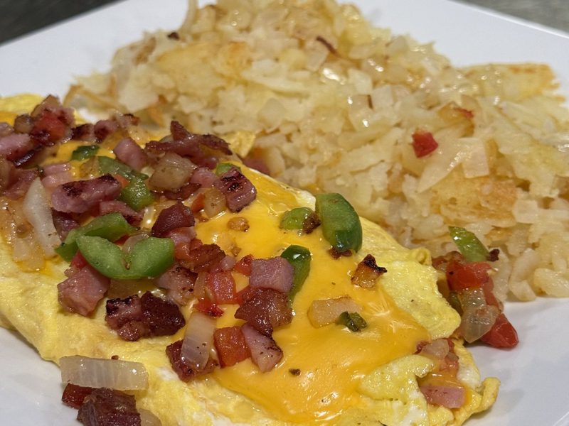 Western omelette with ham, bacon, peppers, onions, and cheese, served with potatoes and toast